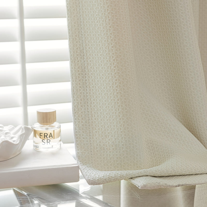 a white shower curtain with a bottle of perfume next to it