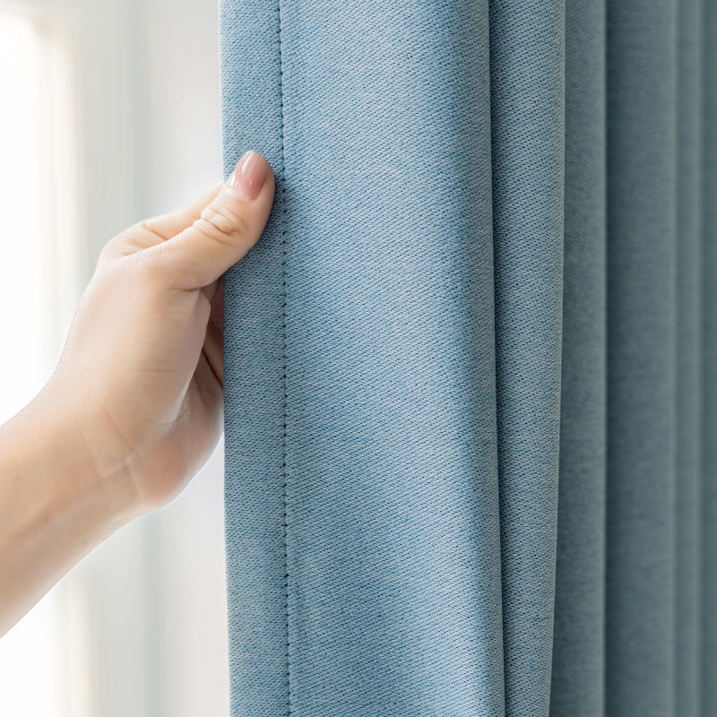 a hand is holding the curtain in front of a window
