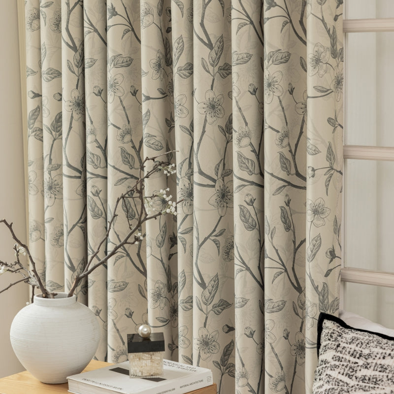 a vase with a branch on a table next to a window
