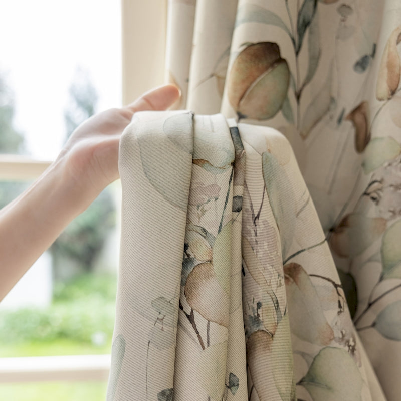 a hand is holding a curtain with a flower pattern