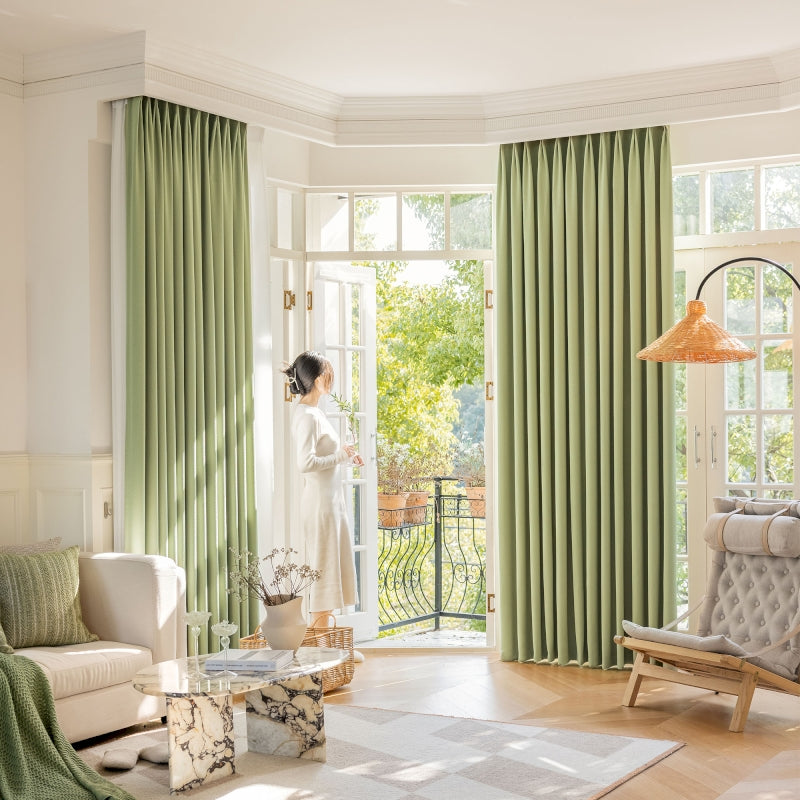 a woman standing in a living room with green curtains