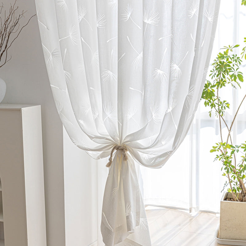 a white curtain hanging from a window next to a potted plant
