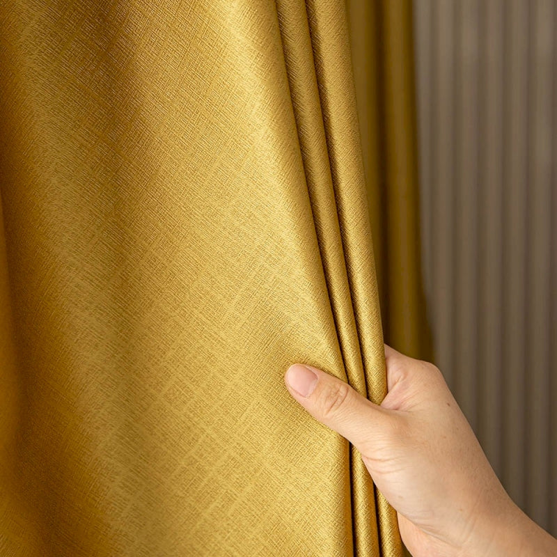 a hand holding a curtain with a gold color