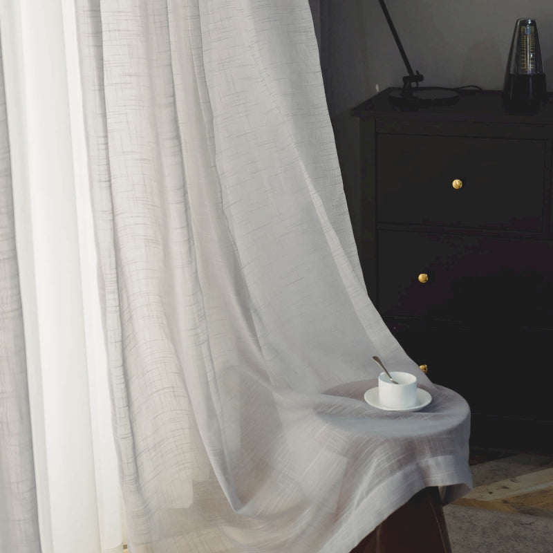 a table with a cup on it in front of a curtain
