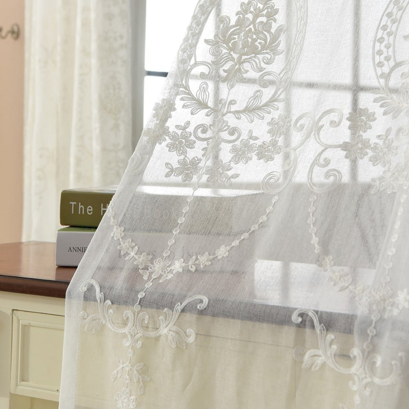 a window with a white curtain and a book on a table