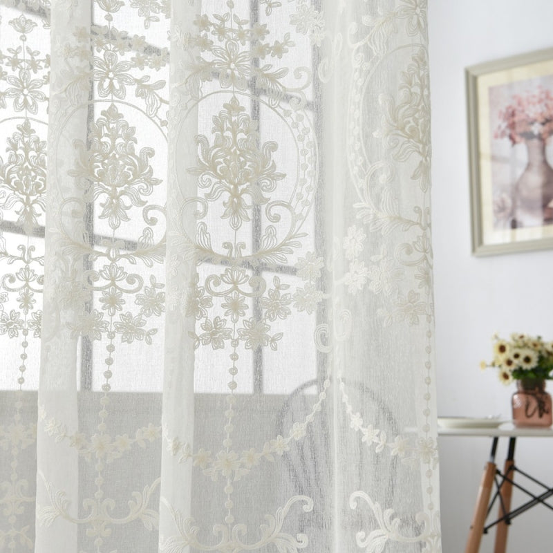 a white sheer curtain with a floral design