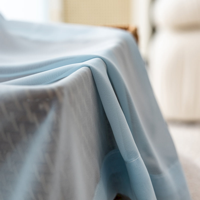 a bed covered with a blue sheet and a white chair
