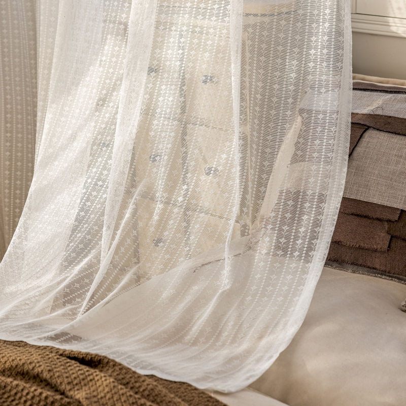 a bed with a white sheer curtain hanging over it