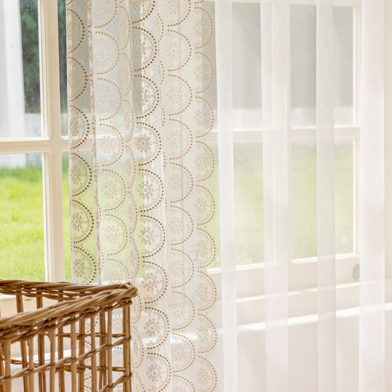 a window with sheer curtains and a basket in front of it