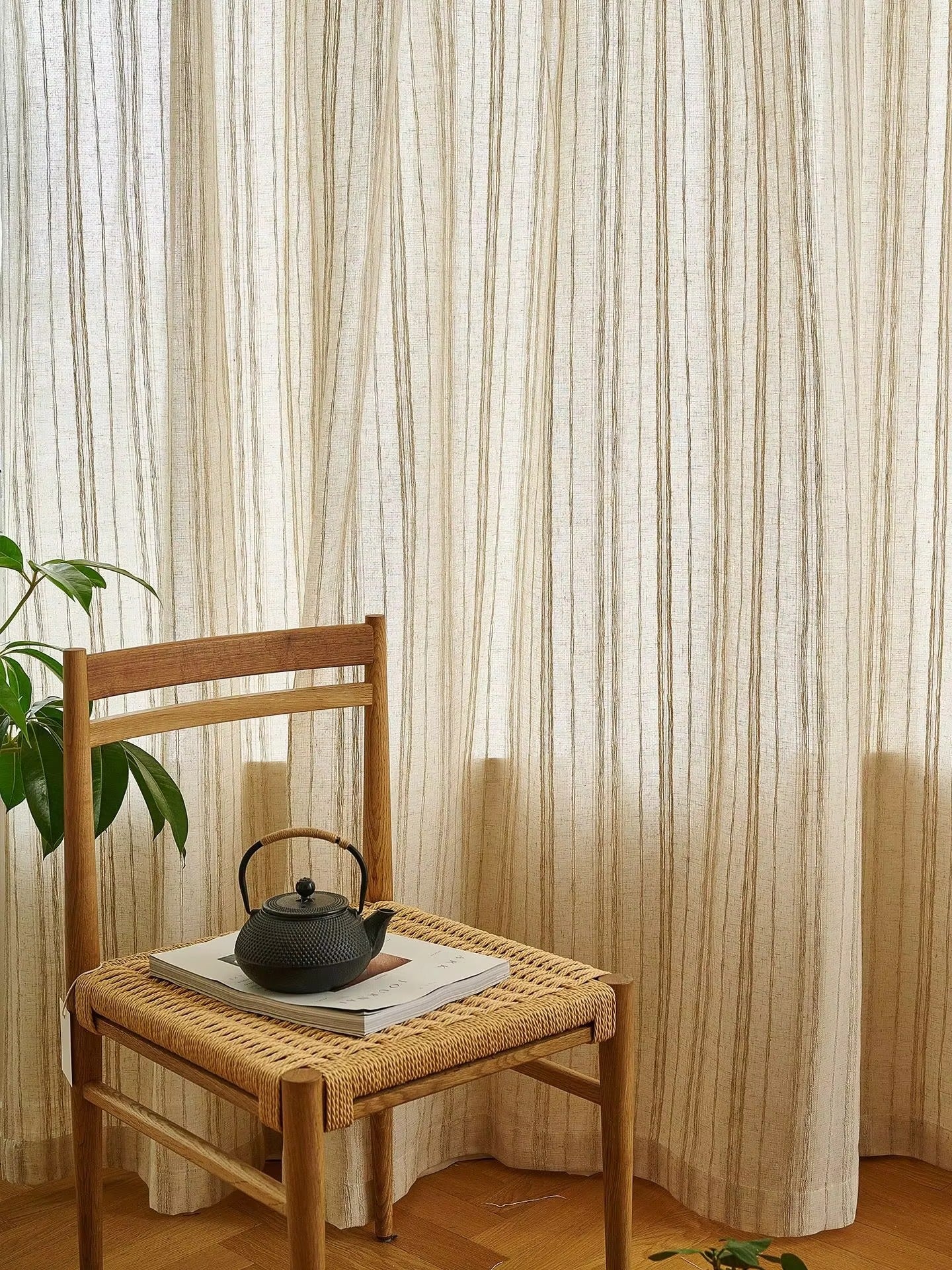 a tea pot on a chair in front of a curtain