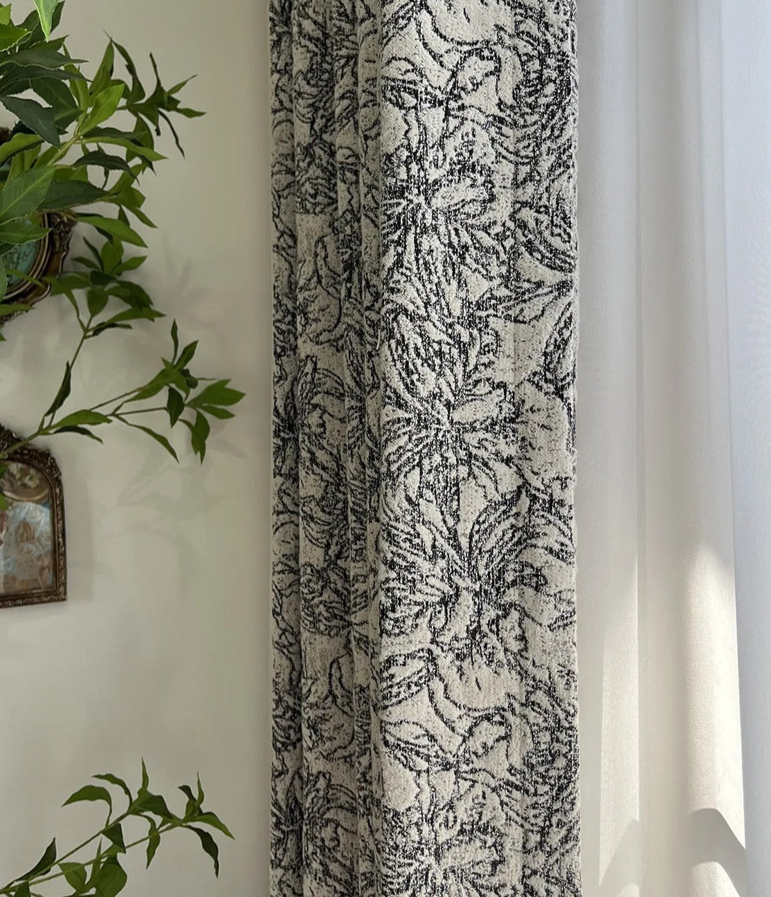 a plant is hanging on a wall next to a curtain