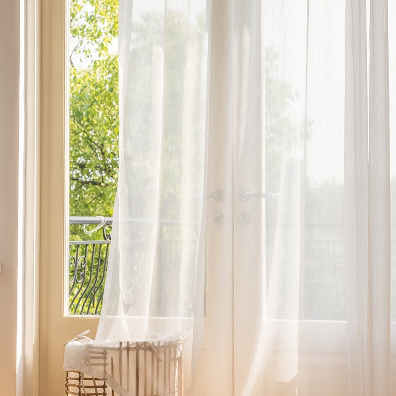 a window with a white curtain and a white radiator