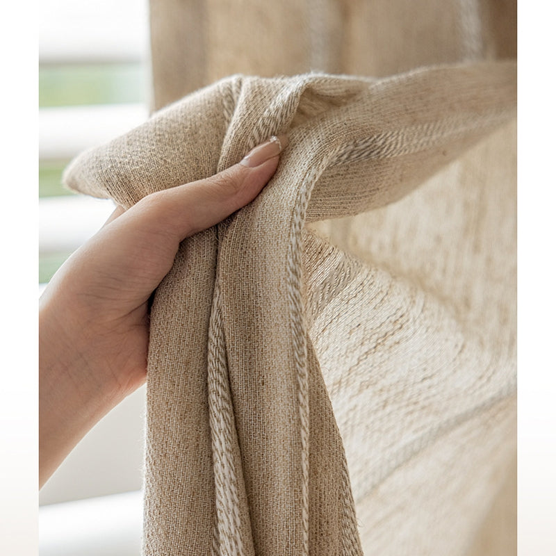 a hand is holding a blanket over a window