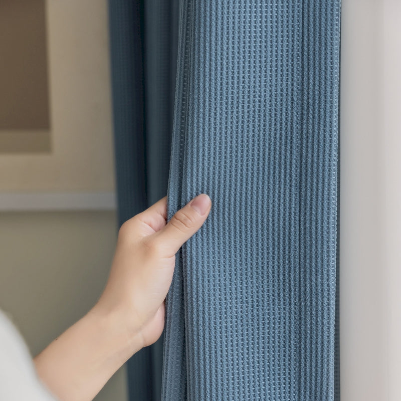 a person is opening a curtain with their hand