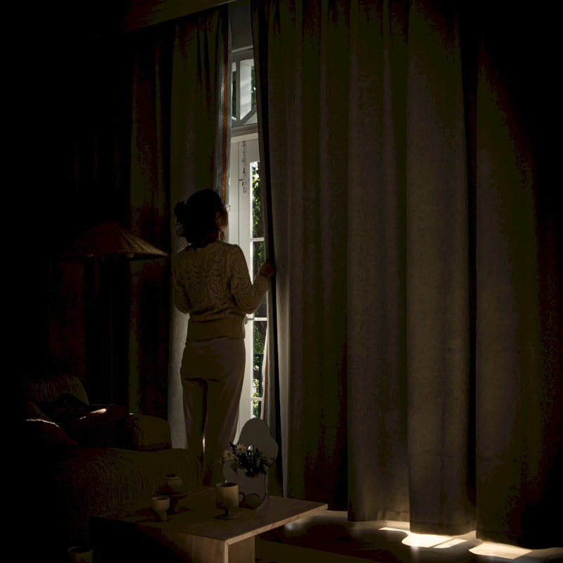 a woman standing in front of a window in a dark room