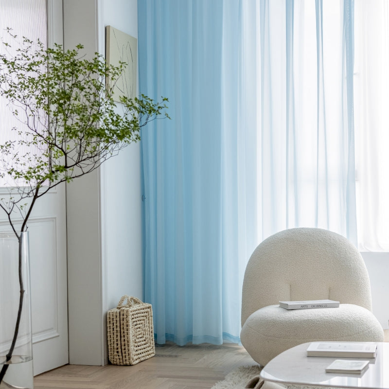 a living room with a white chair and a blue curtain