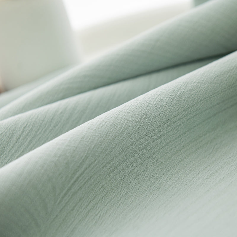 a close up of a bed with a green comforter