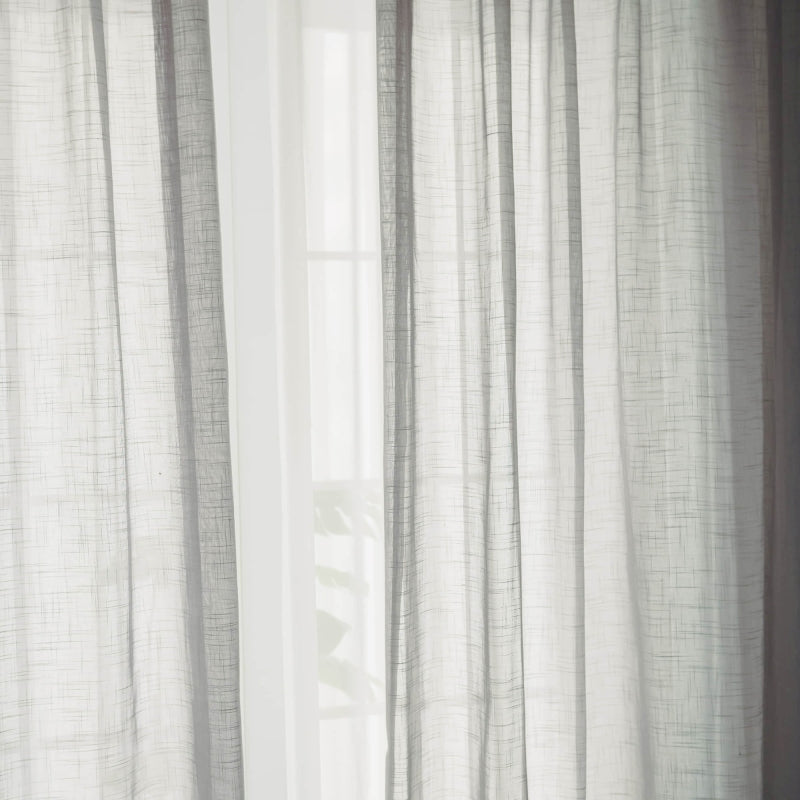 a cat sitting on a window sill in front of a curtain