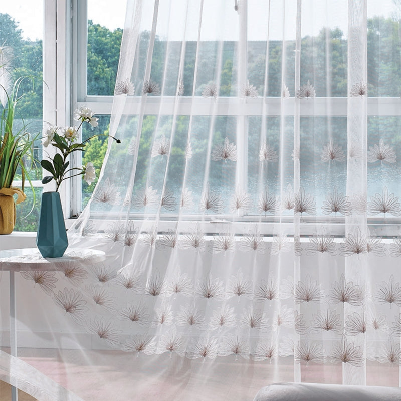a window with a sheer curtain and a vase with flowers