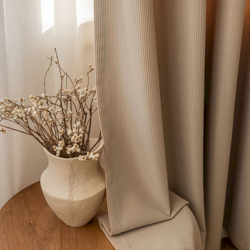 a vase of flowers sitting on a table next to a curtain