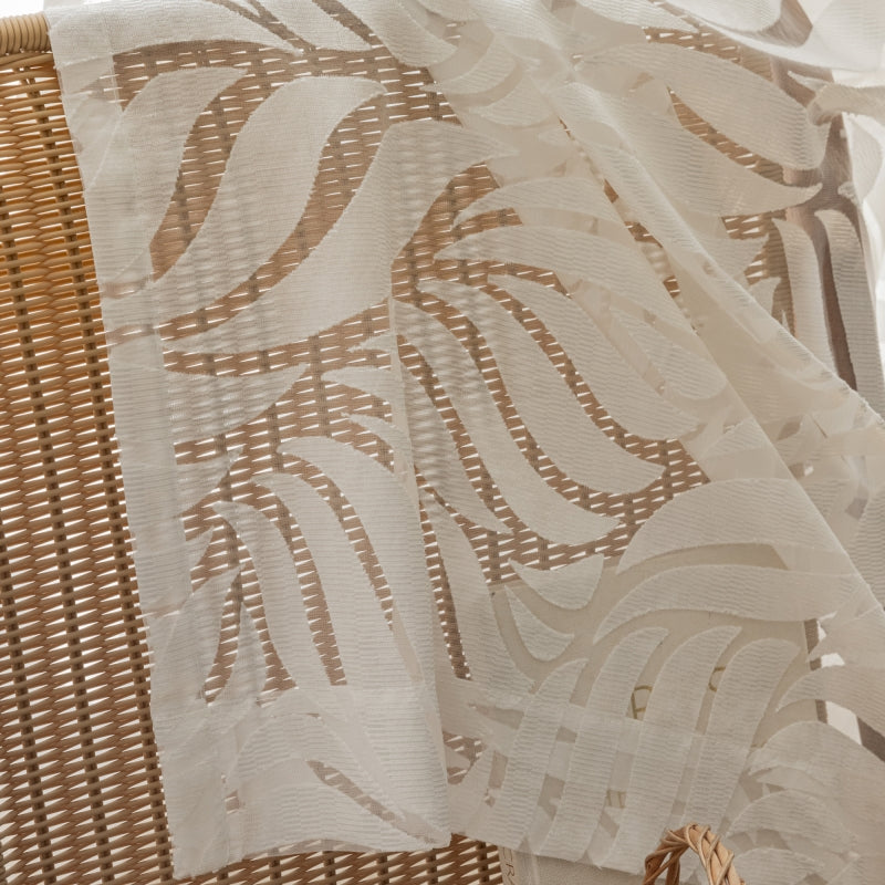 a basket sitting on top of a bed next to a white curtain