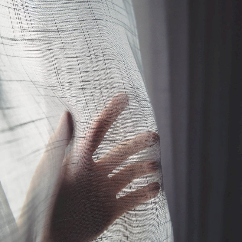 a person's hand is seen through a sheer curtain