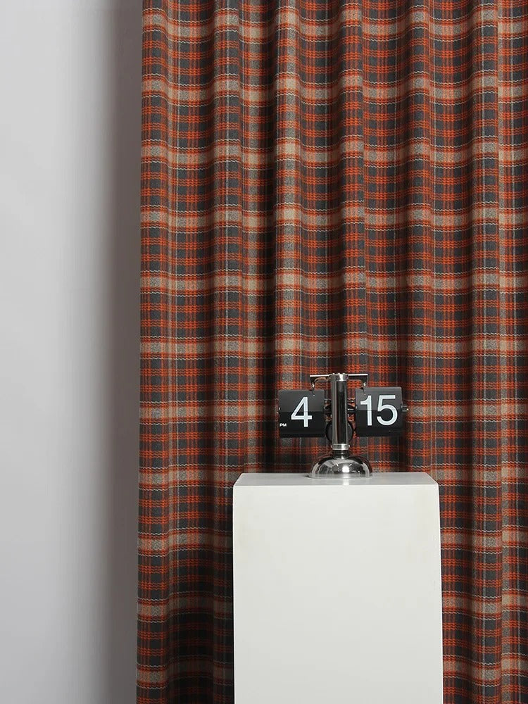 a clock on a pedestal in front of a curtain