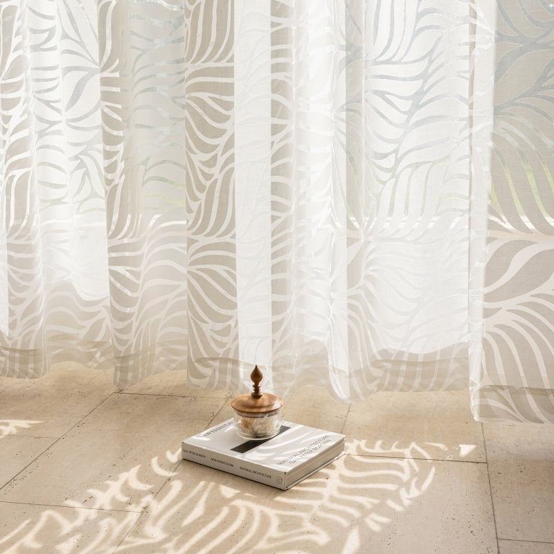 a table with a bowl on top of it in front of a curtain