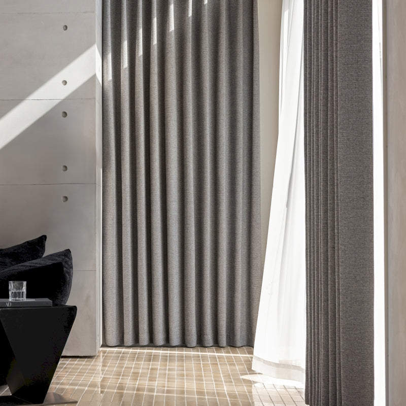 a living room with a black chair and a white curtain