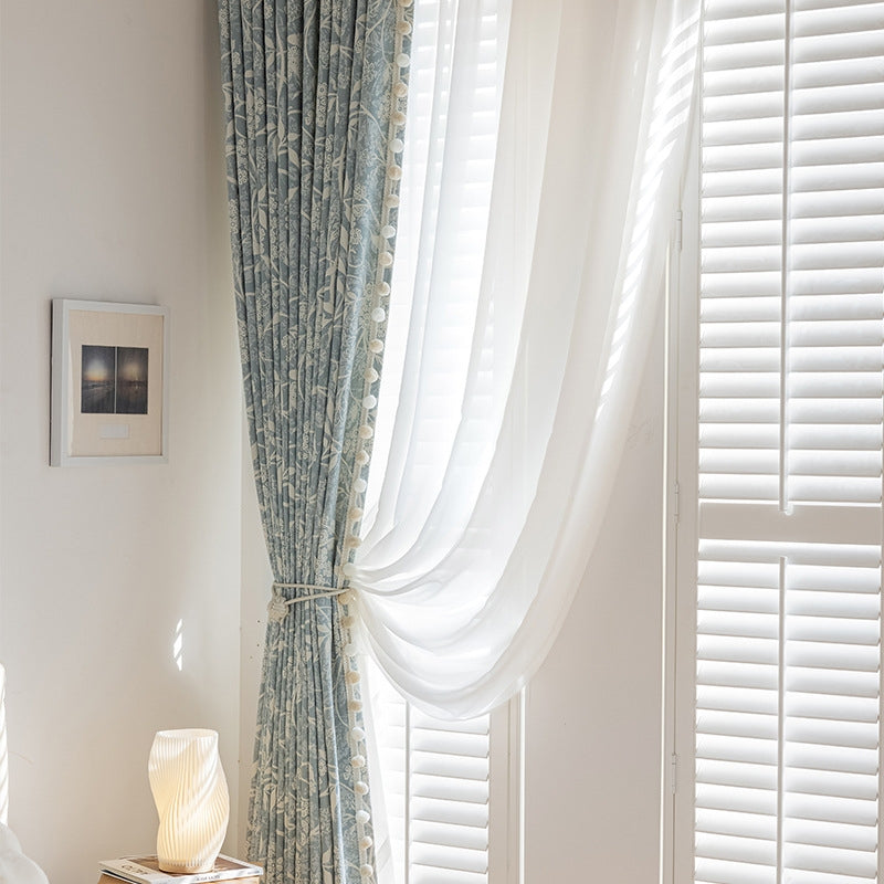 a bedroom with a window covered in white curtains