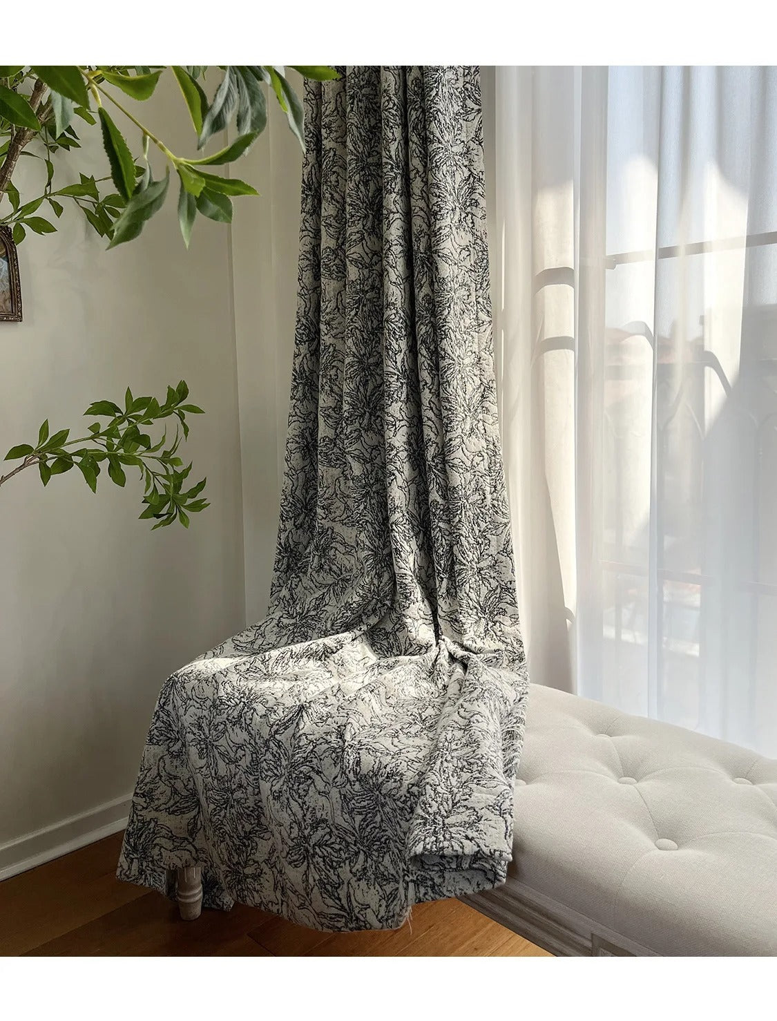 a white couch sitting under a window next to a plant