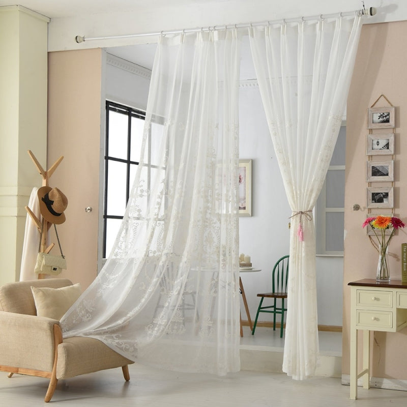 a living room with a chair and a white curtain