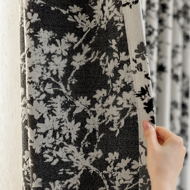 a person is holding up a black and white curtain