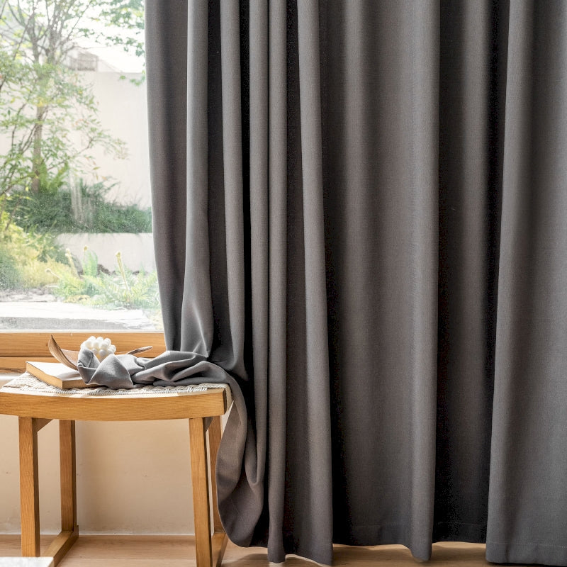 a wooden table sitting next to a window covered in curtains