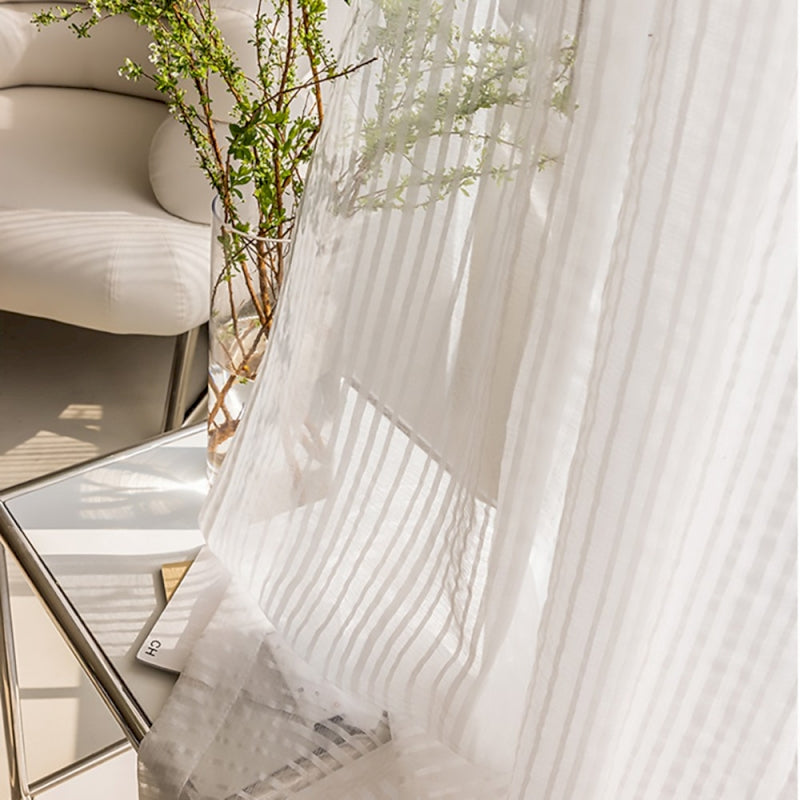 a white chair sitting next to a white curtain