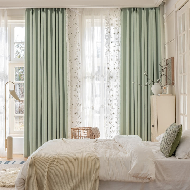 a bedroom with green curtains and a white bed