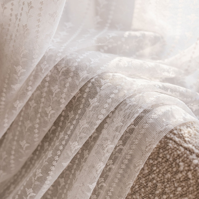 a close up of a bed with white lace on it