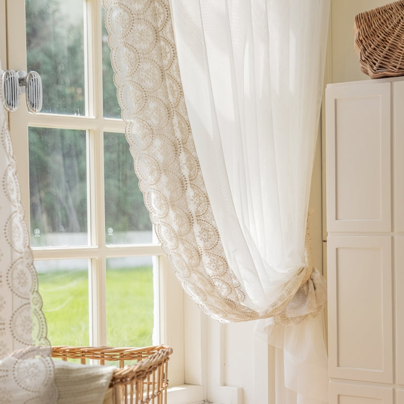 a window with a white curtain and a basket next to it